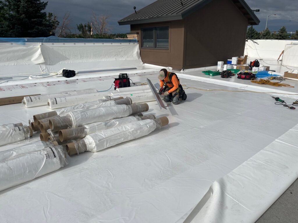 roofer replacing flat roof with single-ply panels on a commercial building in colorado