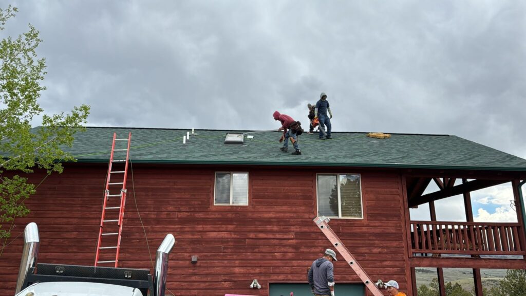 workers on roof doing last touches on a shingle roof replacement